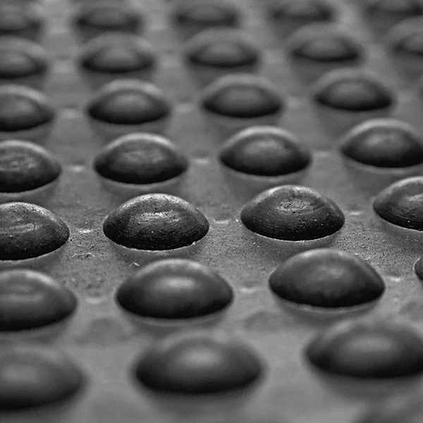Close-up of rubber anti-fatigue mat texture in a garage setting. Textured rubber anti-fatigue mat on a concrete garage floor.
