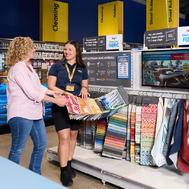 Clark Rubber team member helping customer choose fabric samples. Customer receiving advice about custom cushion fabrics in store