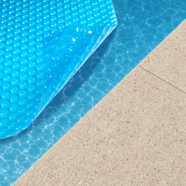 Blue solar pool cover on a backyard swimming pool helping retain heat during cooler weather