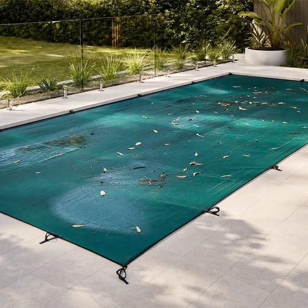 Winter pool cover preventing leaves and debris from entering the water. Some leaves on top of cover.