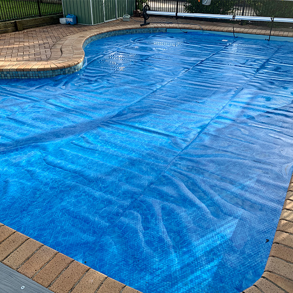 Backyard pool fitted with a protective pool cover in use
